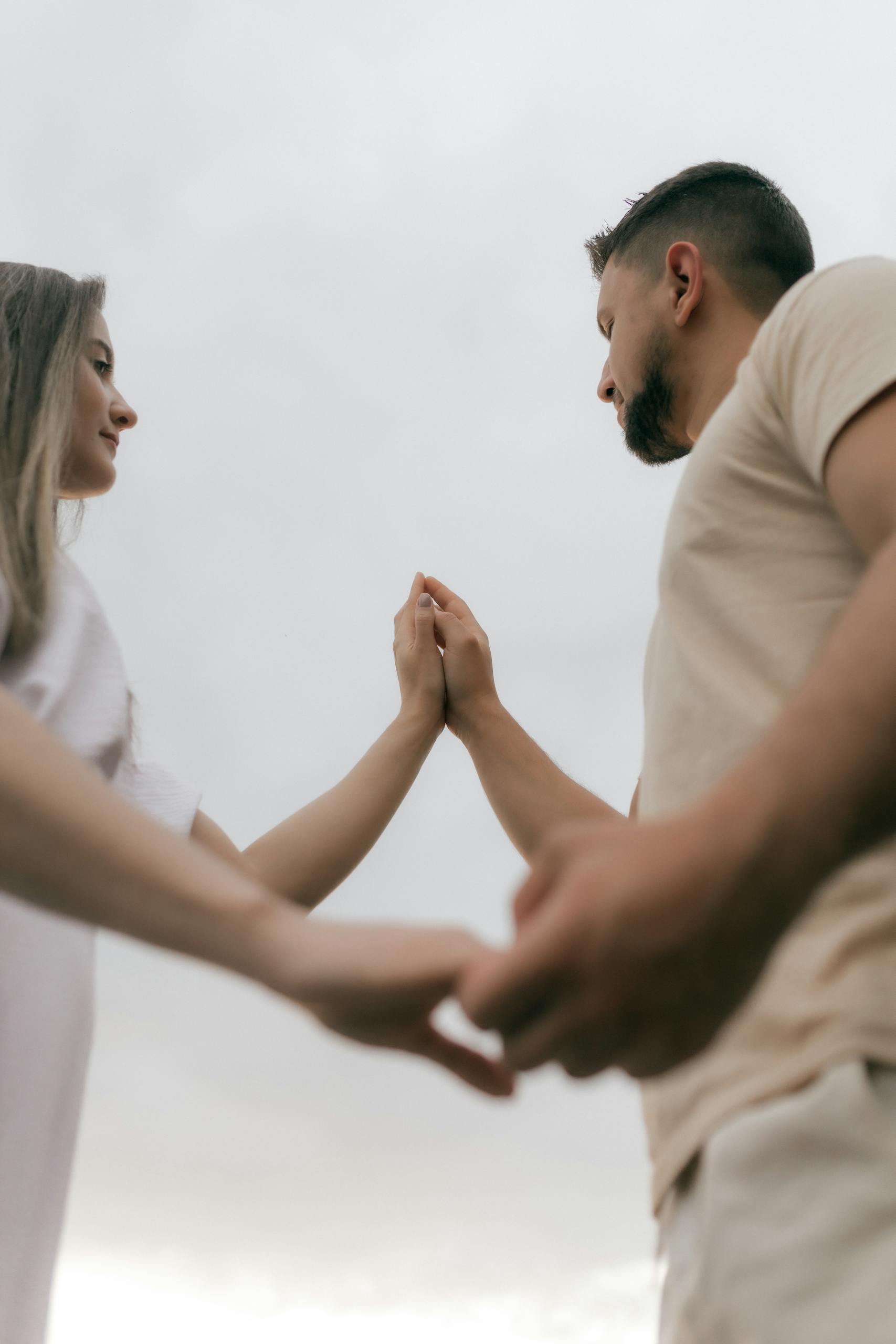 A couple connecting and holding hands against a cloudy sky, symbolizing love and unity.