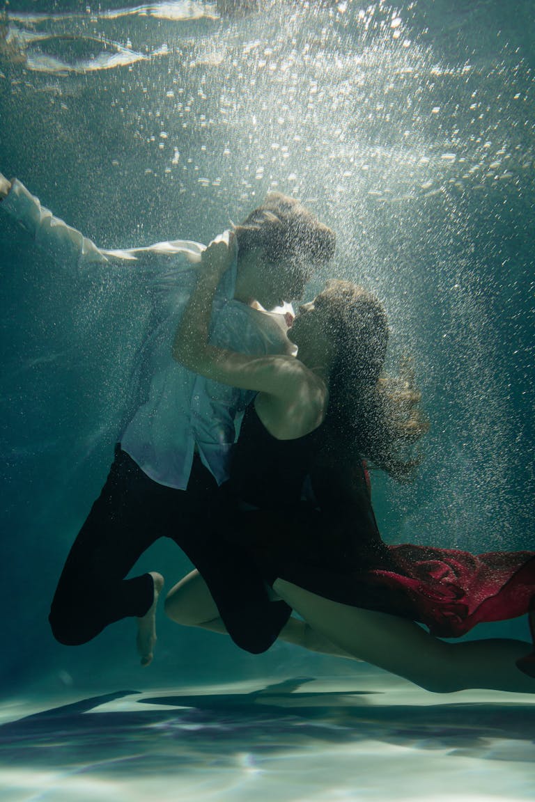 A man and woman share a romantic dance underwater, creating an ethereal and intimate moment.