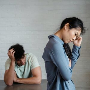 An Asian woman and man feeling misunderstood and frustrated in a relationship indoors.