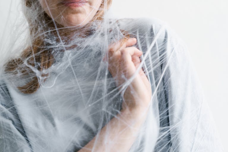 Close-up of a woman tangled in a spider web, symbolizing feelings of entrapment and anxiety.