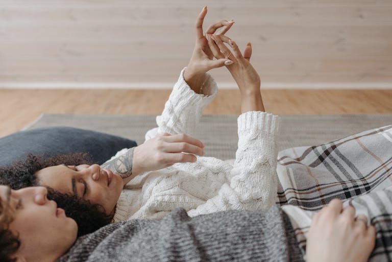 Couple lying on the floor, showcasing engagement ring, embodying love and intimacy.