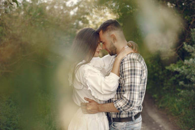 Loving couple gently embracing in a serene natural setting with lush greenery.