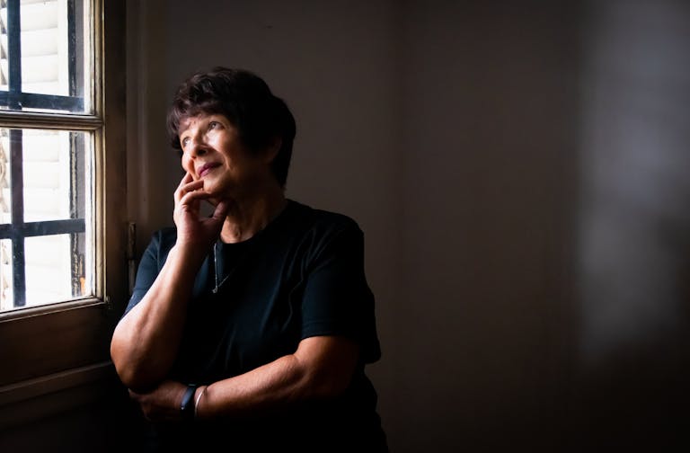 Thoughtful senior woman looking out a window, lost in reflection and quiet contemplation.